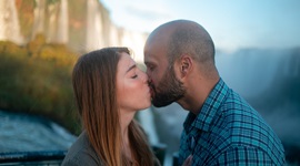 滝を背景にキスをするカップルの写真