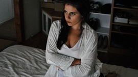 腕を組んでベッドに座っている女性の写真