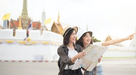 地図を持ち、片方が遠くを指しているアジア人女性の写真